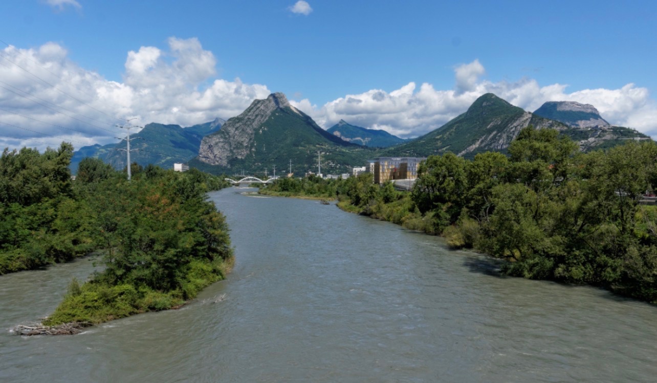 Vue du Drac et de ses digues dans l'agglomération grenobloise, avec les quartiers urbains et les montagnes en arrière-plan, illustrant un exercice de gestion du risque d'inondation organisé les 12 et 13 octobre 2026.