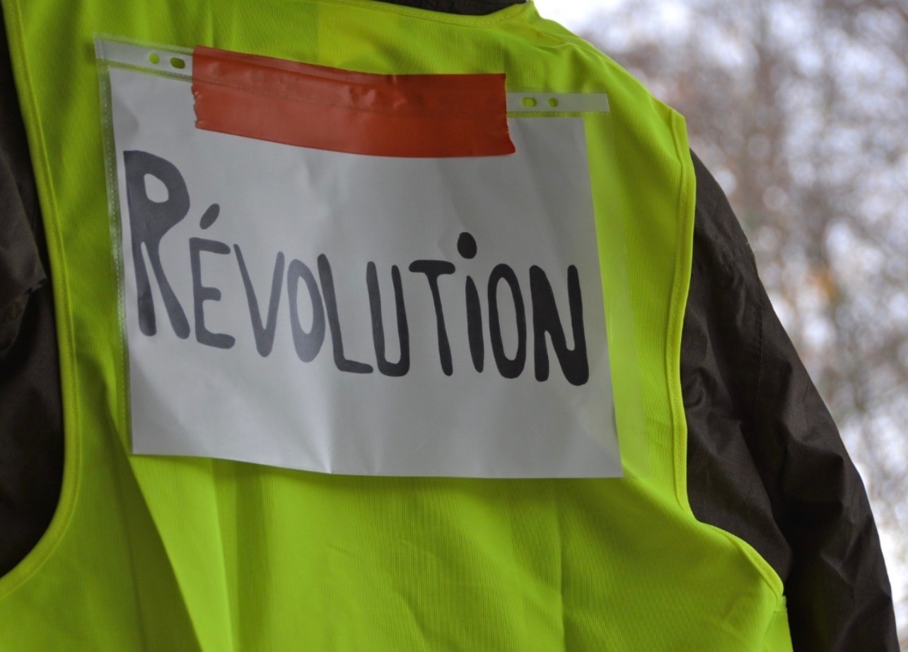 Illustration d'un rassemblement de personnes portant des gilets jaunes sur une place urbaine à Grenoble, pour accompagner l'annonce d'un rendez-vous place Victor-Hugo le 17 octobre 2026.